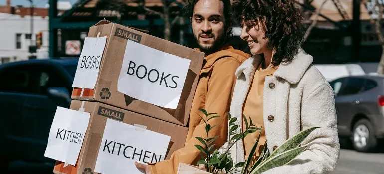 a couple carrying moving boxes for their move to Wheaton