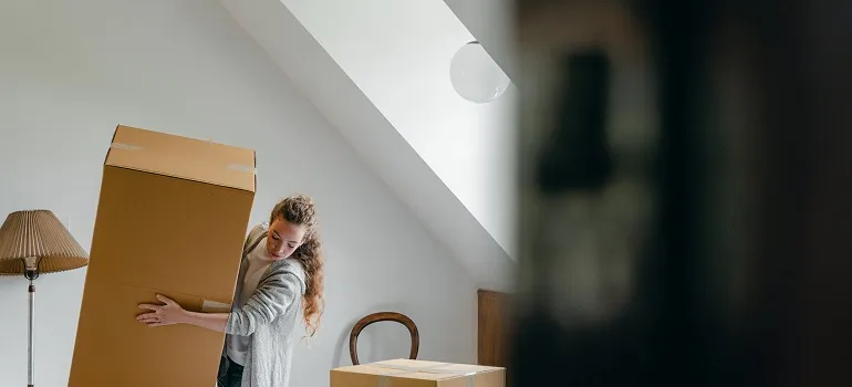 a girl carrying a heavy moving box