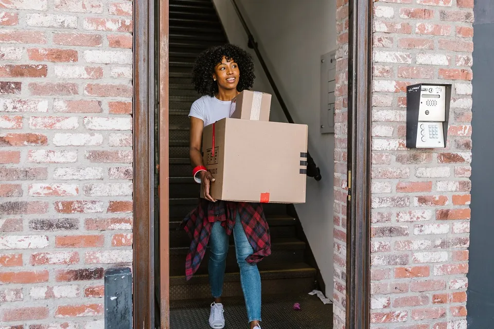 a girl carrying a moving box -moving to a house