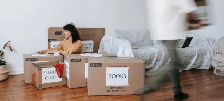 A couple organizing labeled cardboard boxes.