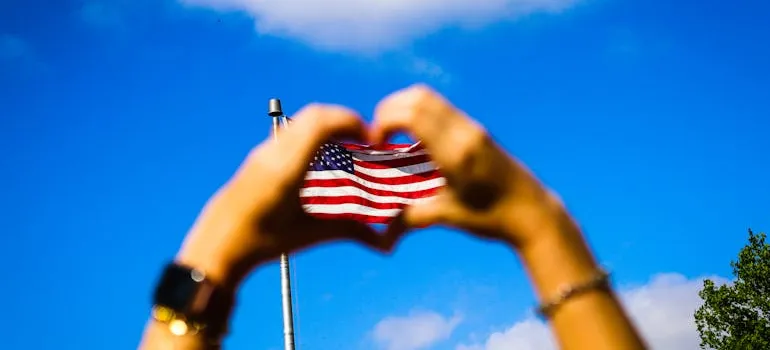A US Flag and a heart formed with hands.