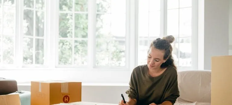 A woman writing something on a big box.