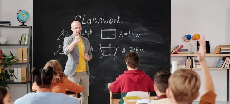 Students and male teacher in a classroom.