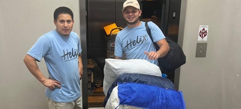 Professional movers with some packed items in front of an elevator.