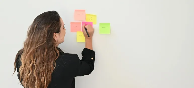 Businesswoman Organizing Tasks with Sticky Notes as you should do before you move your Business from Maryland to Virginia .