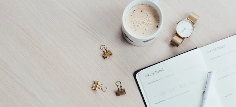A planner on a table next to a cup of coffee to write down a plan when relocating from Silver Spring to Chevy Chase.