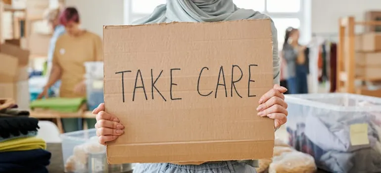 A person holding a sign "Take Care"