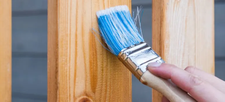 A person painting the fence