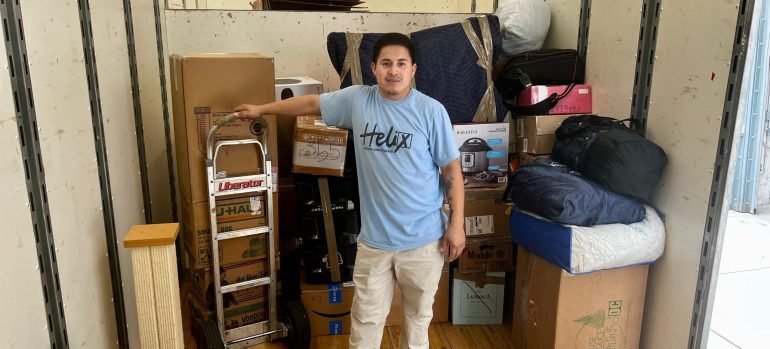A professional mover standing next to packeed boxes ready for moving.