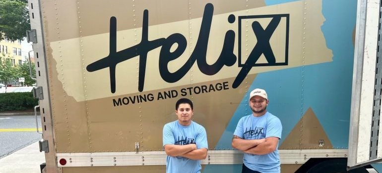 Two professional movers standing nnext to a moving truck.