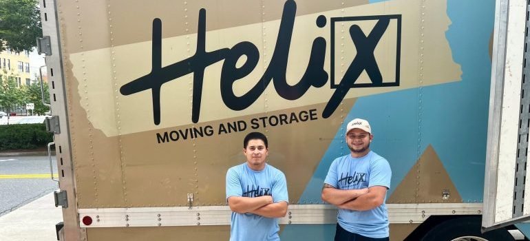 Two professional movers next to a moving truck.