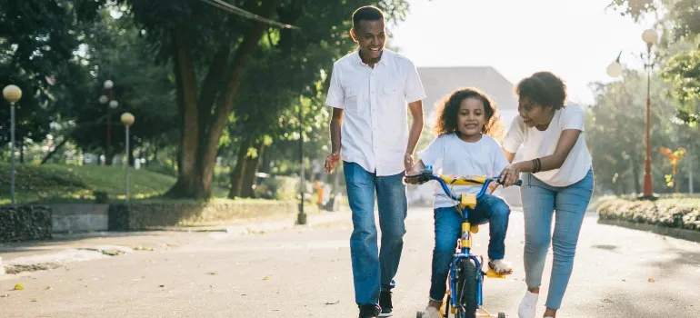 Man Standing Beside His Wife Teaching Their Child How to Ride Bicycle