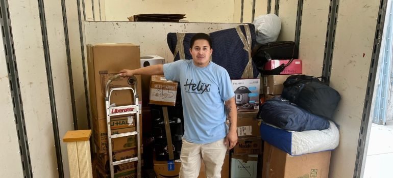 A professional mover next to some items packed and loaded into a moving truck.