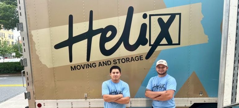 Two professional movers standing next to a moving truck before stress-free moving.