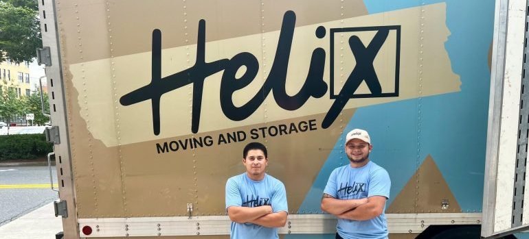 Two professional movers tanding next to a moving truck.