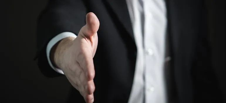 A businessman reaching out with a hand to a person moving out of Maryland.