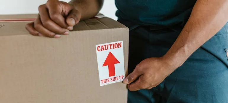 A mover leaning on a box while helping a client who is moving out of Maryland
