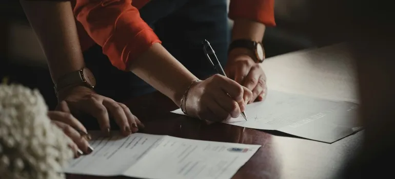 Person signing a contract after finding out that moving from Maryland to Virginia can offer new opportunities.