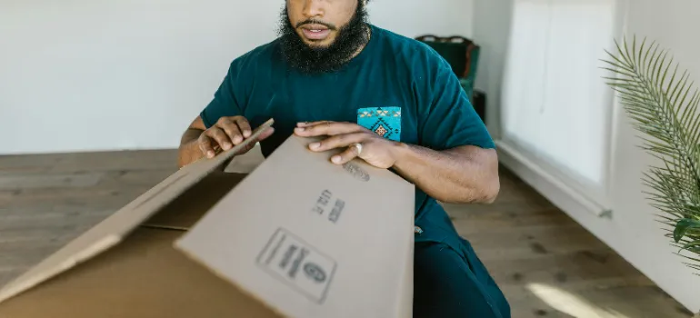 A professional mover packing a cradboard box.